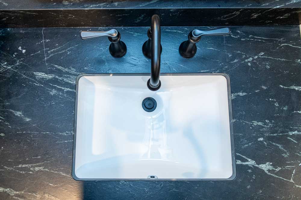 Widespread black faucets with granite countertops.